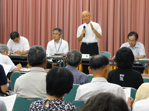 着席する沢山の会議参加者の前で、立って話をする市長の写真