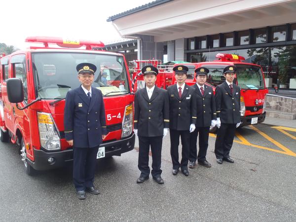 消防車の前で記念撮影している制服姿の市長と団員らの写真