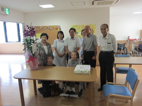 車いすに座る圓谷 房子さんと周りに立つ市長と関係者の集合写真