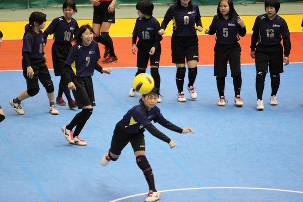 ボールを投げている女の子とその様子を見ている子供たちの写真