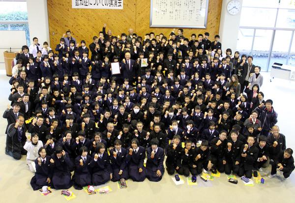 こぶしを握り締めポーズをしている生徒たちと教師の集合写真を上から写した写真