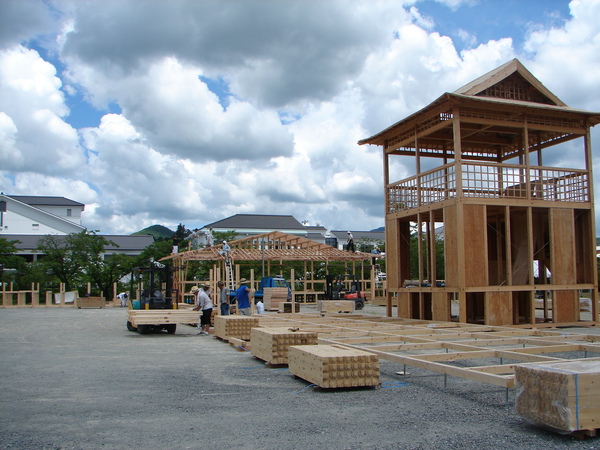 木造ヤグラの前でフォークリフトが木材を運んでいる写真