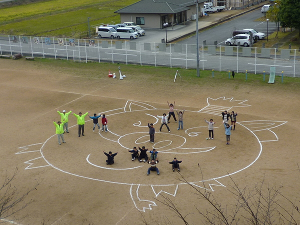 西紀北小学校5・6年児童による「体験学習」測量機器を使って篠山市のマスコット「まるいの」を校庭に大きく綺麗に描いた写真