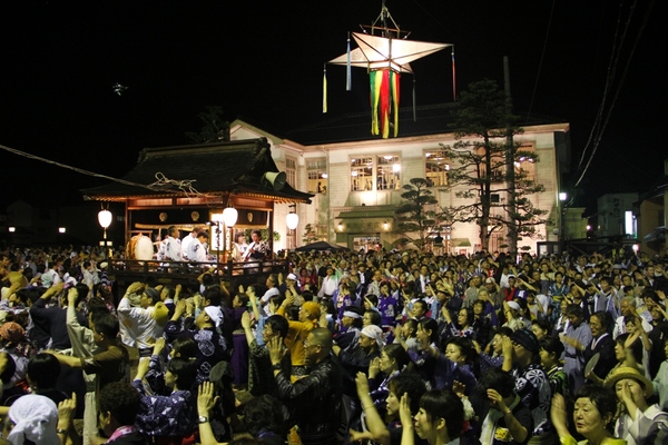 山車の周りで手を挙げて郡上おどりを踊っている多くの市民の写真