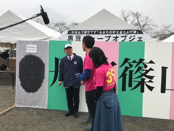 大きなパネルのところで男女のアナウンサーと市長が会話をしている写真