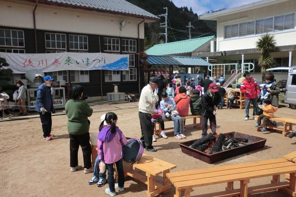 校庭に大きな焚き火があり周りにはベンチが並べられ暖を取る人たちの写真