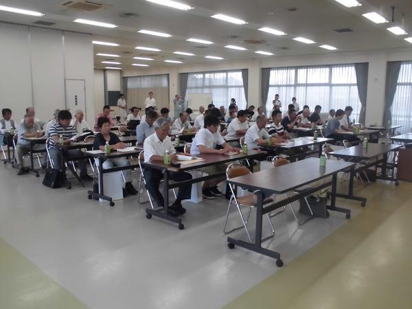 兵庫県茶業振興大会の参加者が席に着いており、机の上に広げられた資料に目を通している様子の写真