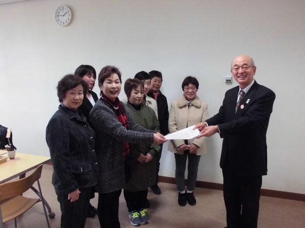 7名の女性参加者が市長の前に立ち代表者が市長へ紙を渡している写真