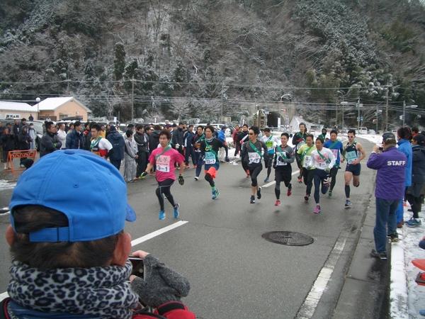 あたり雪景色の中、緑のタスキをした選手たちが走っている写真