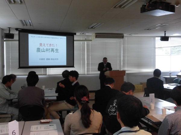 スクリーンには農山村再生とあり、前で男性が話をしている様子を参加者が聞いている会議の写真