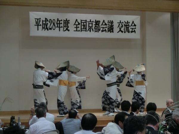 白い着物におけさ笠をかぶった6名の女性が舞台の上で日本舞踊を踊っている写真