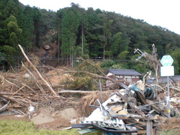 山崩れが起こっており、流された流木やがれきが積み重なっている様子の写真