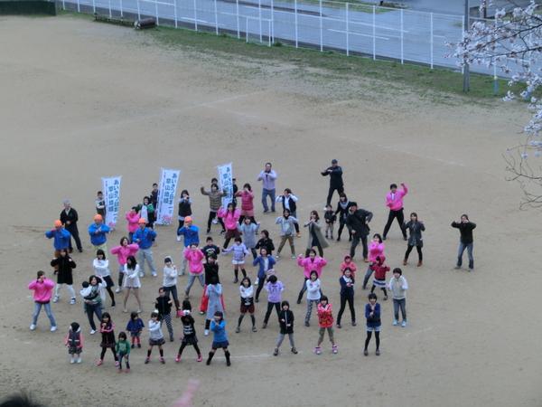 篠山市立西紀北小学校の子供達が運動場で大人と踊っている姿を上から撮影している写真