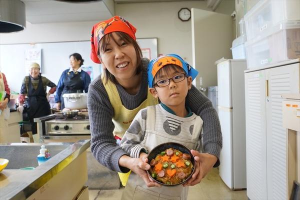 神田 拓翔くん・神田 恵子さんがまめまめ おこのみ丼を持っている写真