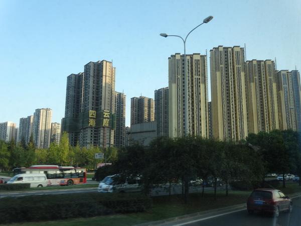 成都市の町中の高層ビル群と車が行きかう道路の写真