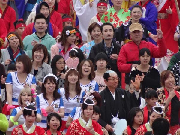 様々なコスチュームや法被を着た市民の間に紛れた紋付き袴を着てちょんまげのカツラを被った市長が総踊りに一緒に参加している写真