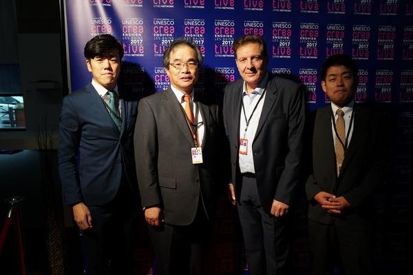 ドミニクロラン アートセンター館長と副市長たちが背広姿で4人がならび一緒に記念撮影をしている写真