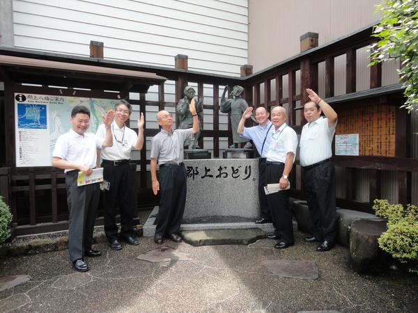 郡上踊りの石造の前で手を頭の上にあげ石造と同じポーズをしている市長たちの写真