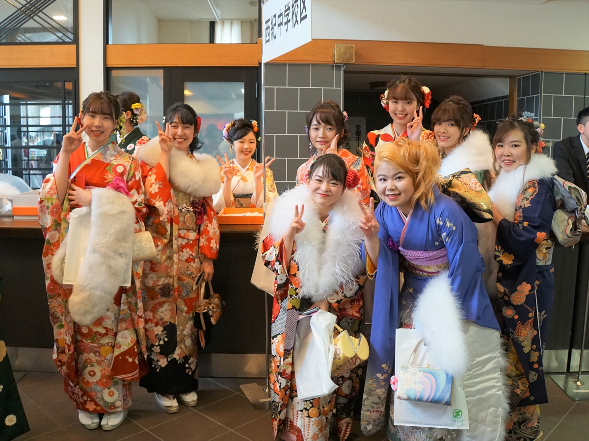田園交響ホールのロビーの西紀中学校区の受け付け前で新成人の女性の方たちが笑顔でお写真を撮っている様子