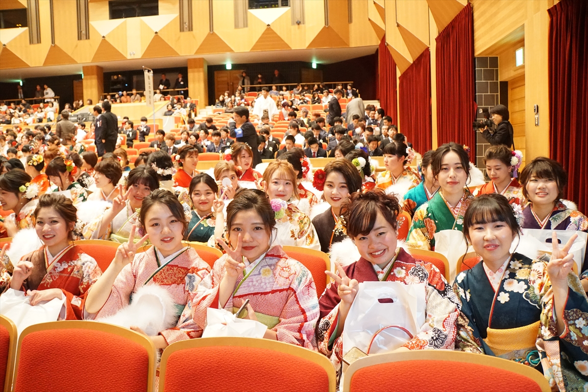 田園交響ホールの客席で、カメラに向かって笑顔でピースをしている女性の新成人のみなさん・客席の様子