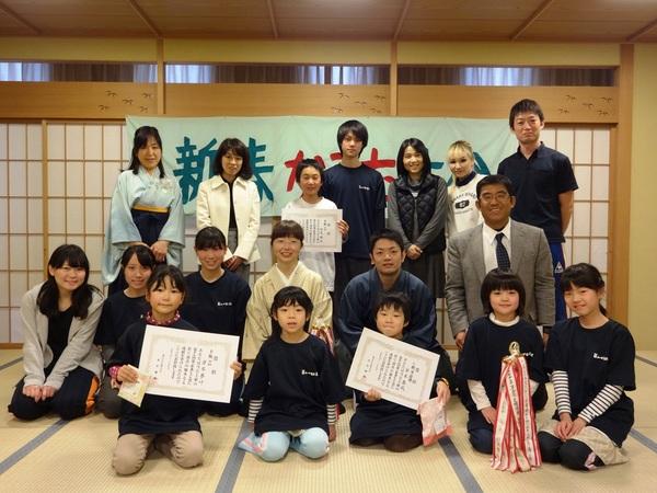新春かるた競技大会で表彰を受けた小学生は表彰状を手に持ち他の参加者と保護者が岸田さんを囲んでいる集合写真