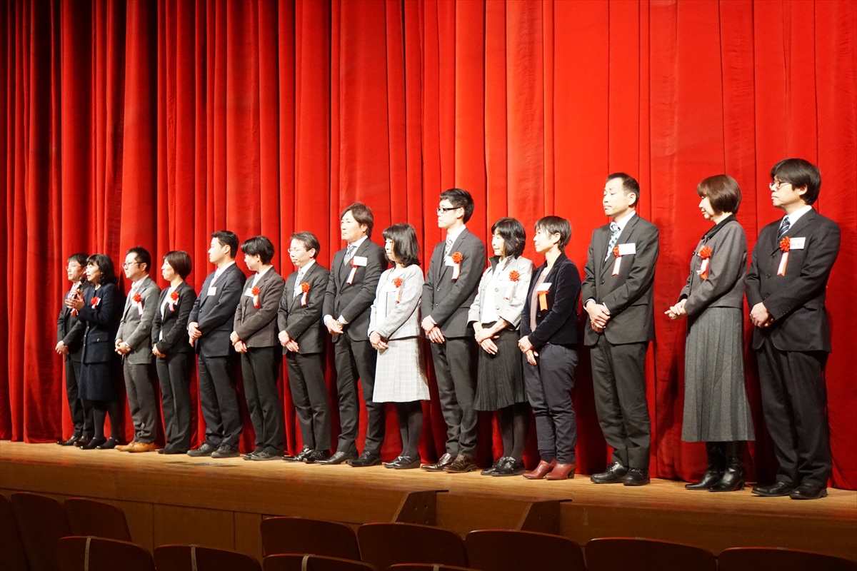 田園交響ホールの舞台上の赤い幕の前で来賓の方々が立っている