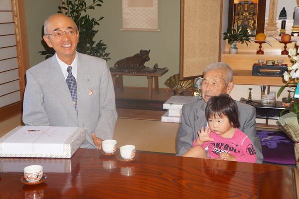 大西さんがひ孫さんを膝の上に抱いて、市長と一緒に映っている写真