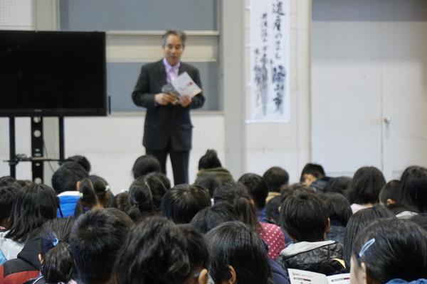 男性が資料を手に子供達の前でお話ししている写真