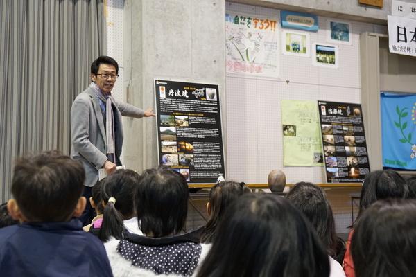 丹波が紹介されたボードを男性が手で示しながら子供達に説明している写真