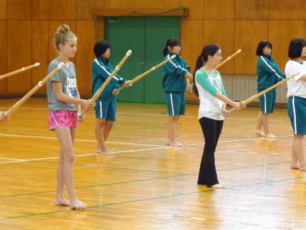留学生が西紀中学校の体操服姿の生徒と一緒に竹刀を持ってかまえている写真