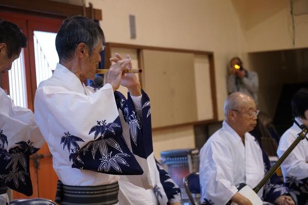 白に紺色の絵の浴衣を着た男性たちが、三味線や竹笛を吹いている写真