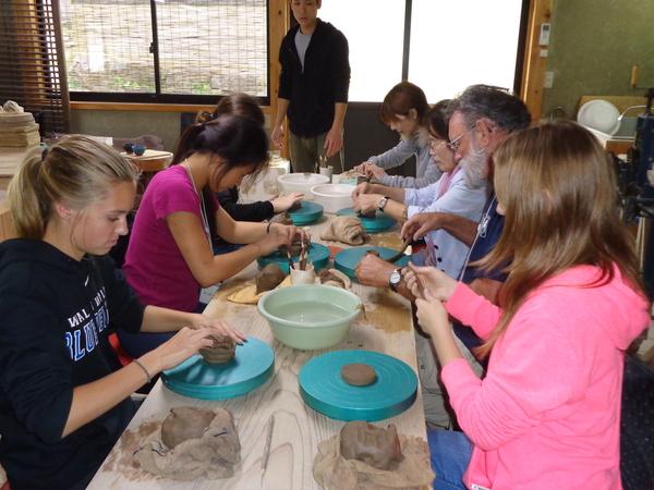留学生達がみんなで陶器づくりの体験をして粘土をこねている写真