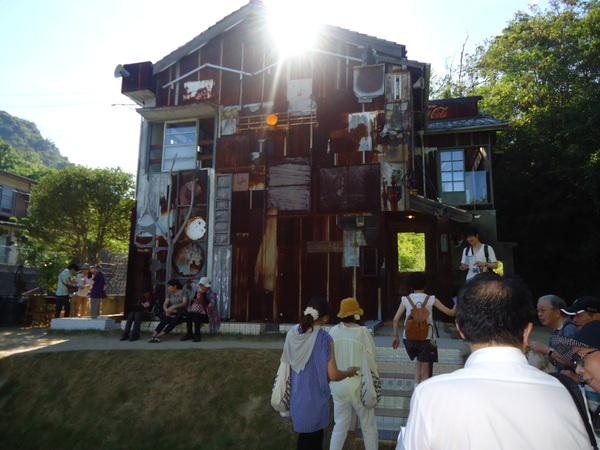 パイプや、木の枝などで装飾されたアート館を見学にきている人達の写真