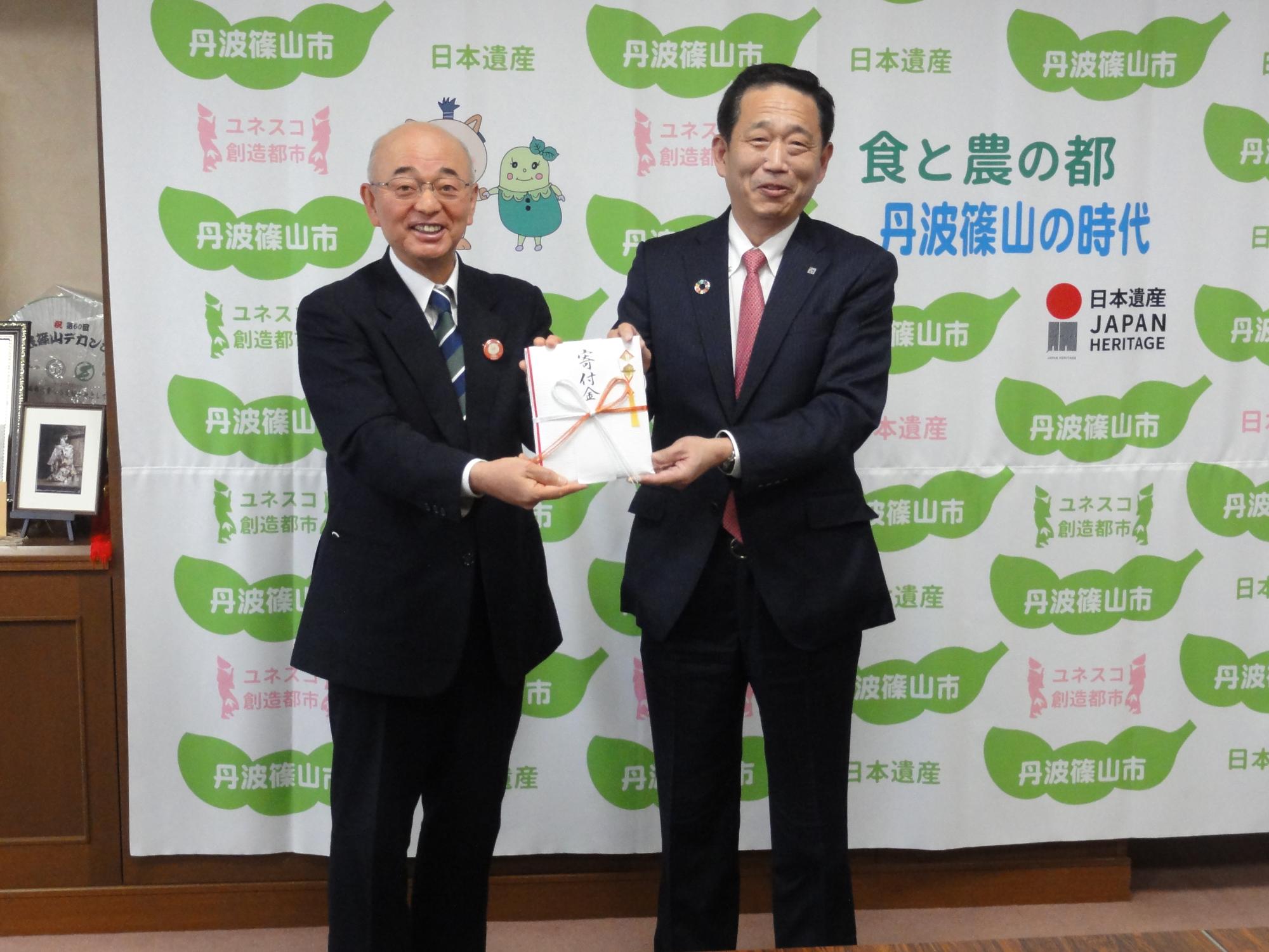 寄附目録を手にする酒井市長と足立理事長