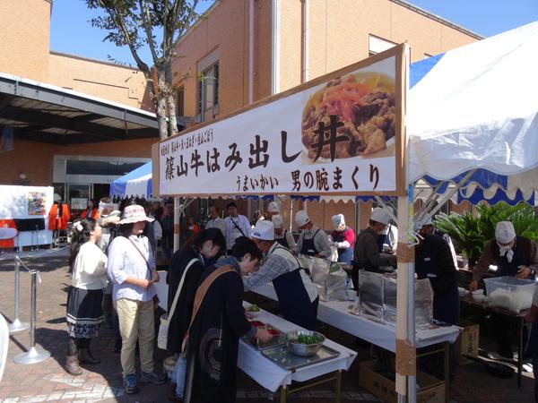 牛丼売り場で野菜を入れる人々と順番を待っている人々の写真