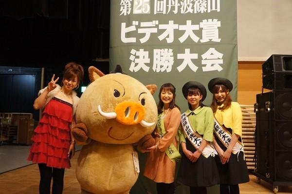 赤いドレスを着た女性と「まるいの」篠山観光大使の3人で記念写真