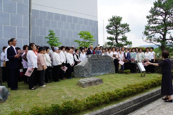 女性の指揮者を前に、多くの方が童謡・唱歌を歌っている写真