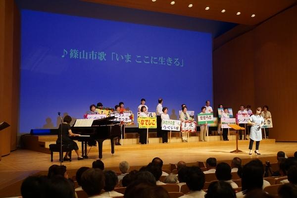 舞台上にて「なでしこ」「うぐいす」「せせらき」などそれぞれプラカードを持って発表している写真