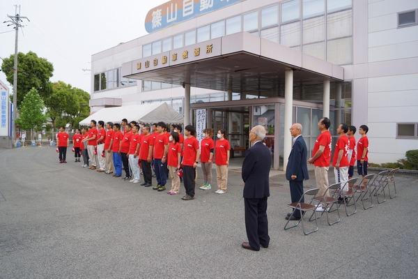 篠山自動車教習所の前で整列し、赤い服を着た職員たちと市長の写真