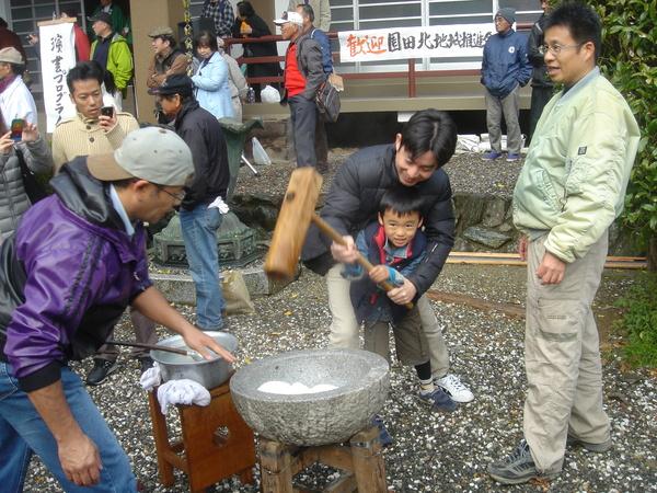 杵で餅つきを楽しむ親子の写真