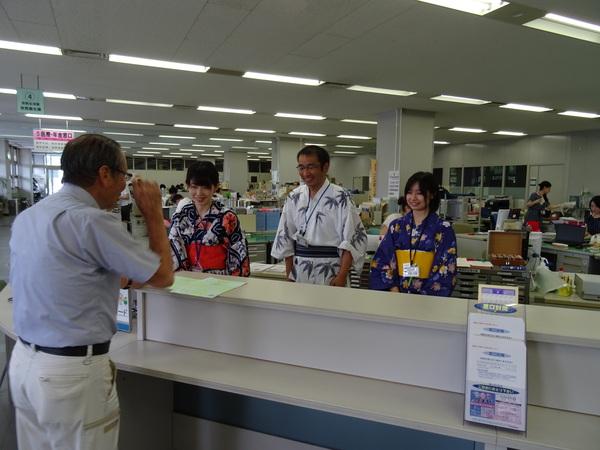 デカンショ祭の日、涼しげな浴衣姿の女性職員2名と男性職員1名が窓口対応している写真