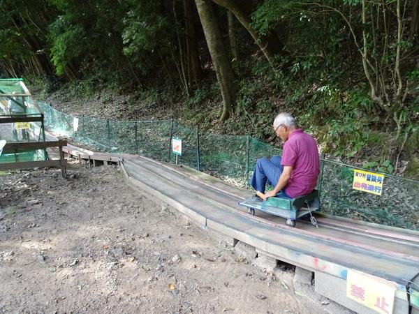 台車に男性が座っており、レールの上を滑り降りている様子の写真