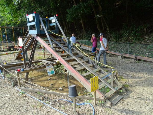 滑り台の昇り階段が木材で作られており、ロープを伝って登れるようにロープも設置してあり、滑り口の台は青色で塗られている滑り台の写真