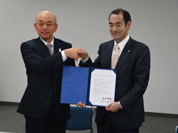 酒井市長と谷口市長が握手をして、青い証書を持って写っている写真