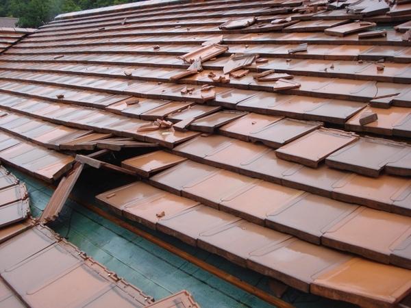 激しい雷雨と突風で、茶色の屋根の瓦が破損している写真
