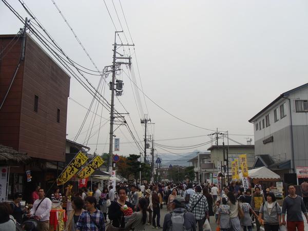 ポン菓子や焼き栗の旗が立っていて、ぎっきりのお客さんが歩いている写真