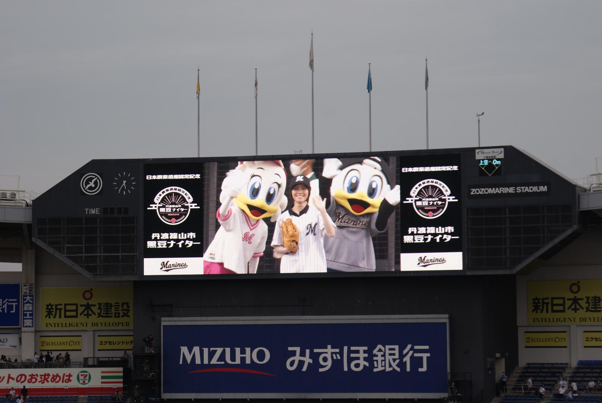 球場のスクリーンに千葉ロッテのマスコットと始球式をした女性がアップで写っている