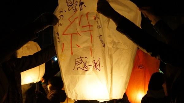 絆、感謝と手書きで書かれたランタンを両手で持っている写真