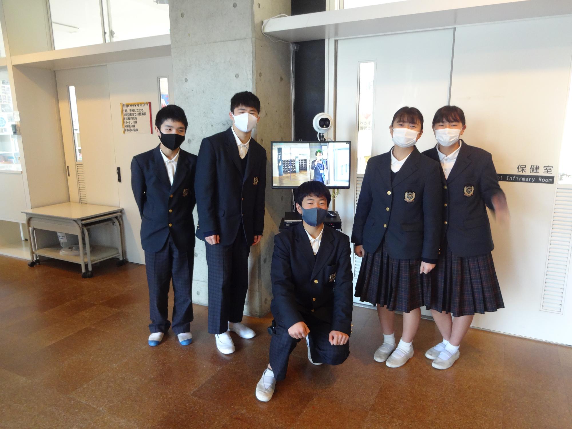 サーモグラフィーカメラの前で並ぶ3人の男子中学生と2人の女子中学生