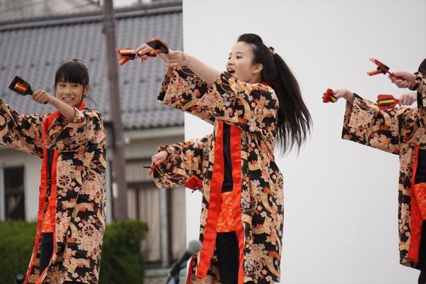 黒地に花柄の着物を着て両手を水平に上げ鳴子を持ち踊っているチームの写真
